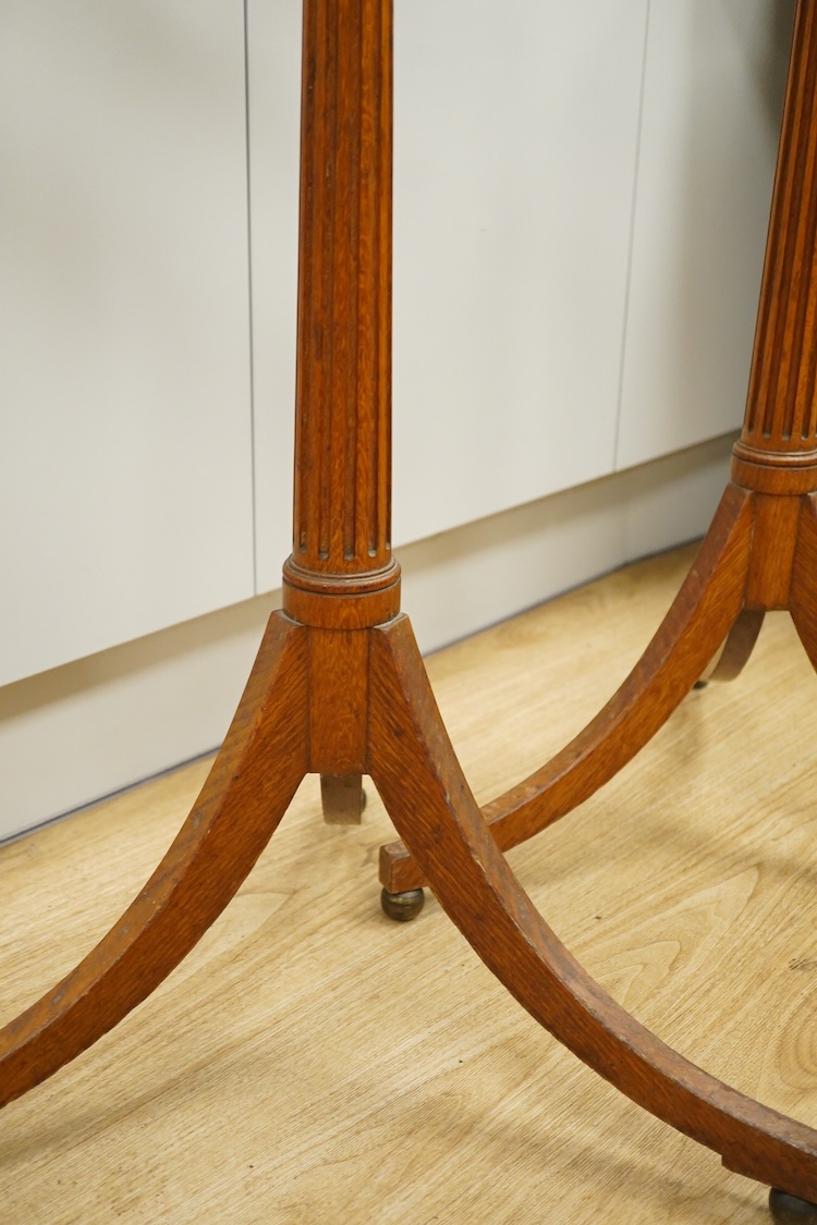A set of three early 20th century oak music stands, all with fluted pedestal supports and tripod legs with brass feet, adjustable height music desks, maximum overall height when extended 137cm, the angle of the desks is